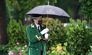 A members of staff shields under an umbrellas during day four of Royal Ascot.