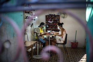 Two women sit inside a home nail salon in Havana
