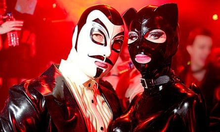 Guests, a man wearing white mask and a masked woman in a catsuit, at Torture Garden's club night. London.