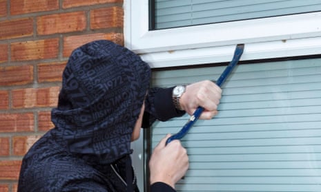 a man trying to force open a window on a house