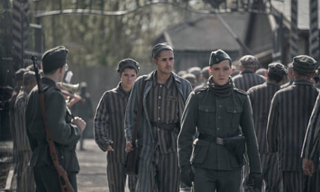 Lali Sokolov (Jonah Hauer-King) in striped uniform walks through Auschwitz with the Nazi officer Stefan Baretzki (Jonas Nay)