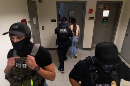 a person in a tactical vest escorts a detained woman to a stairwell