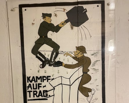 A cartoon German soldier with gigantic mallet fends off a British soldier as he tries to climb a cliff