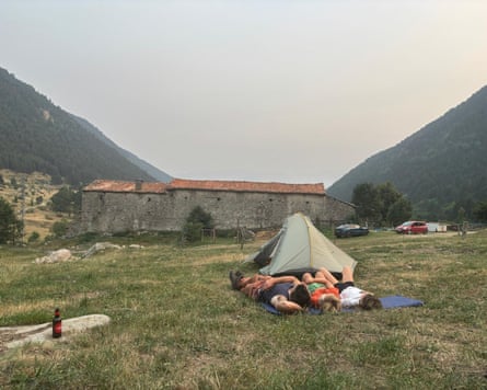 People lying on a matt near, with a building and mountains in the background