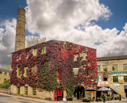old renovated three-storey mill building with chimney, covered in autumnal red ivy