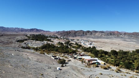 A settlement and trees in a desert landscape with hills in the distance