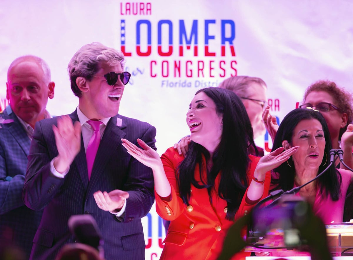 Yiannopoulos and Loomer applaud while smiling on stage, with a 'Laura Loomer for Congress' backdrop behind