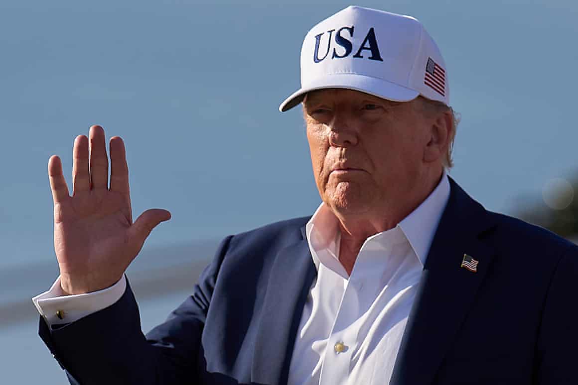 Donald Trump wearing a ‘USA’ cap and waving.