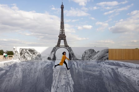 A woman poses in a trompe-l’oeil art installation by JR, set up at the Trocadero in front of the Eiffel Tower, in May 2021.