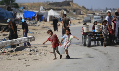 Displaced Palestinian children carry water in a makeshift camp in Khan Yunis on the Gaza Strip, May 2024
