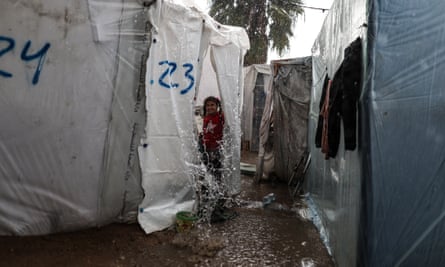 Child between make-shift tents as water pours down