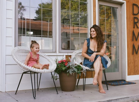 woman and young girl sit in white chairs outside building and smile