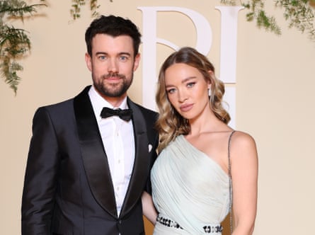 Whitehall in a dress suit and Horner in a white dress off one shoulder.