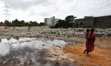 An woman walks past contaminated water at a landfill on the outskirts of Bangalore in 2015.