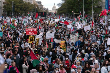 large crowd holds up signs that say ‘ceasefire now’ and ‘free palestine’