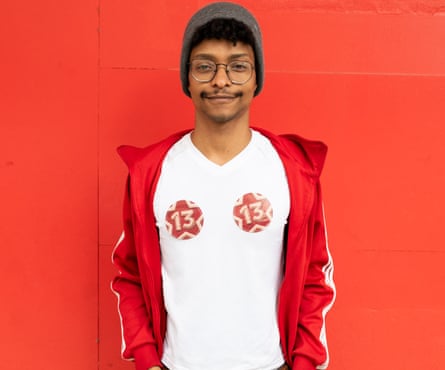 A young man stands in front of a red background.
