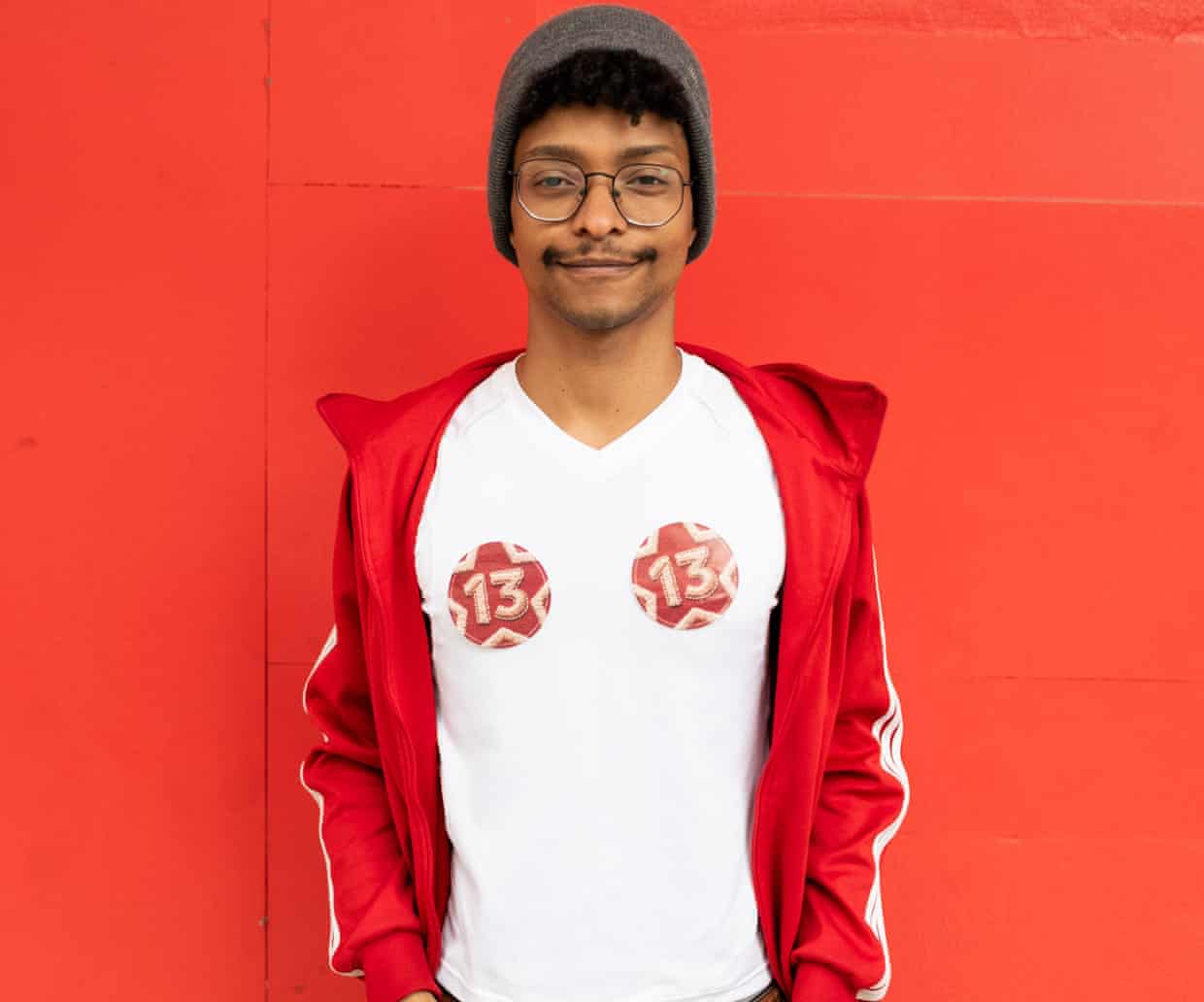 A young man stands in front of a red background.