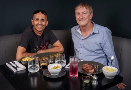 Two men sitting side by side at a restaurant table