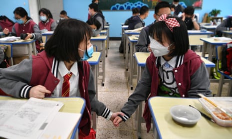 Students wearing face masks chat in a classroom in Kunming, Yunnan Province of China. Many schools around China have reopened.