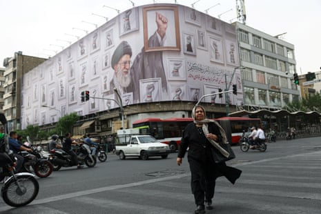 A woman walks near a billboard with an image of the late Iranian supreme leader Ayatollah Ali Khamenei, in Tehran, Iran.