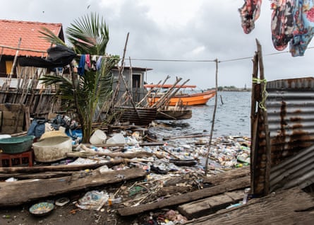 Plastic waste litters the shore between houses.