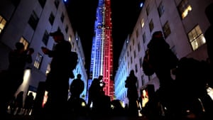 People stop for photographs in front of the Rockefeller Center, which is illuminated with patriotic lighting