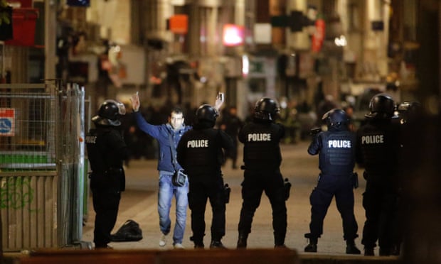 A man raises his arms to French police in the Paris suburb of Saint-Denis during the manhunt for the surviving terrorists who killed 129 people in November.