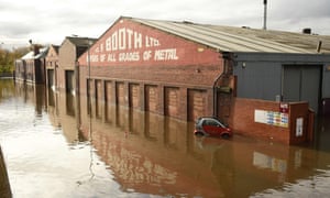 An abandoned car is pictured in flood water surrounding buildings in Rotherham.