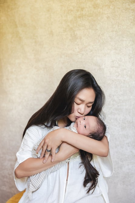 A woman holds a baby and kisses him gently on the cheek