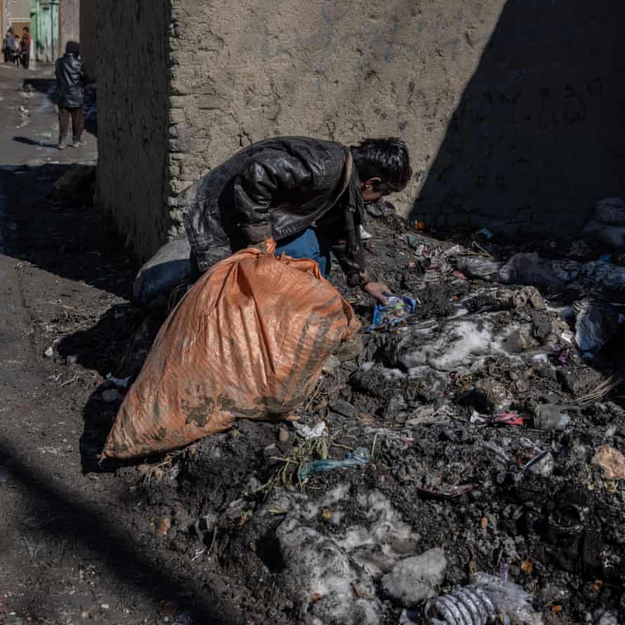 A boy picks through a heap of rubbish on the side of a street