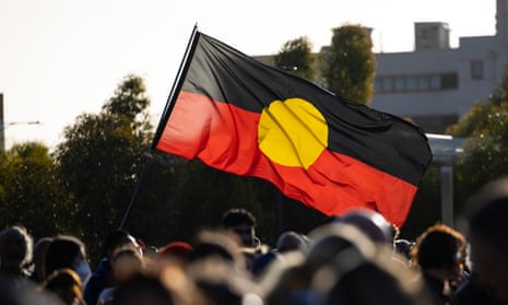 An Aboriginal flag being waved above a blurred crowd