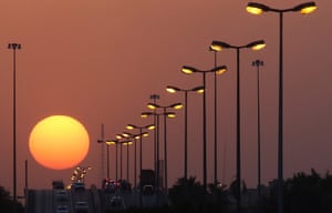 The sun sets over a highway in Kuwait City.
