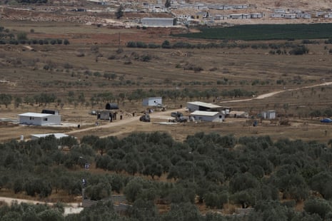 An Israeli military Jeep patrols by some roadside buildings