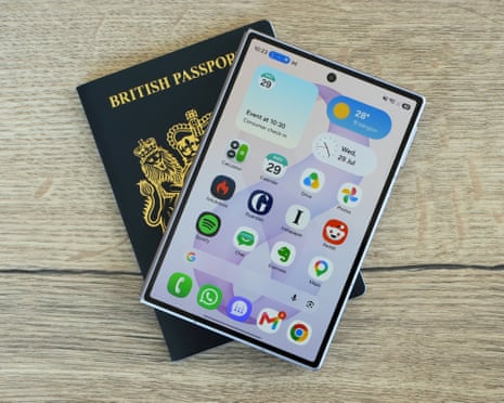 A closed Samsung Galaxy Z Fold 8 smartphone with home screen visible rests atop a British passport on a wooden table.