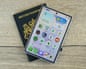 A closed Samsung Galaxy Z Fold 8 smartphone with home screen visible rests atop a British passport on a wooden table.
