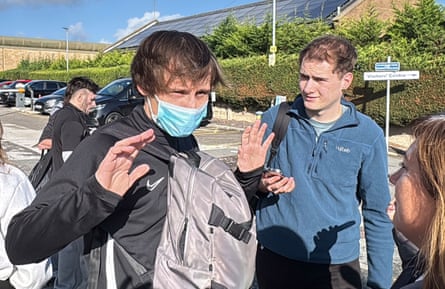 Laverack, wearing a medical face mask, raises his hands as he speaks to a man and a woman