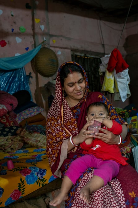 Mukhti Shanker with a baby girl on her lap who is drinking from a bottle