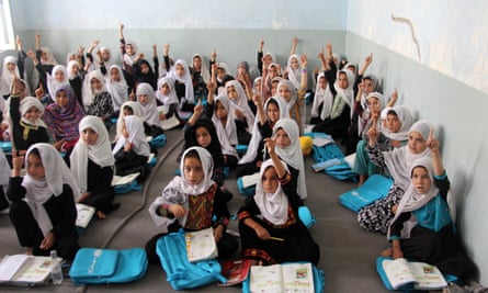 A large class of girls in headscarves sitting on the floor