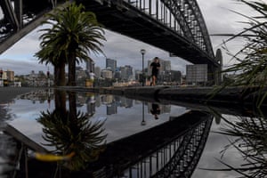 People exercise past the Sydney Harbour Bridge as a torrential downpour lashed the city