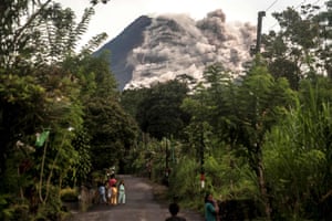 Local residents look up at Mount Merapi as the Indonesian volcano continues to spew out rocks and ash