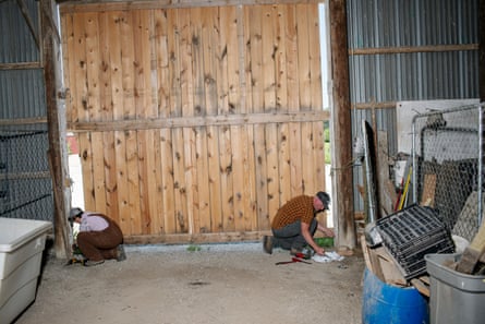 Two people kneel at either side of a barn door.