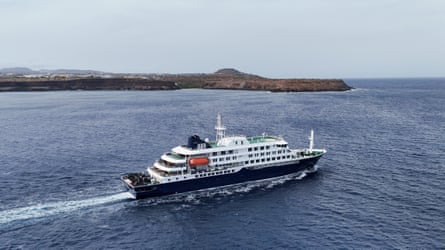 A small cruise ship at sea passing by a coastline