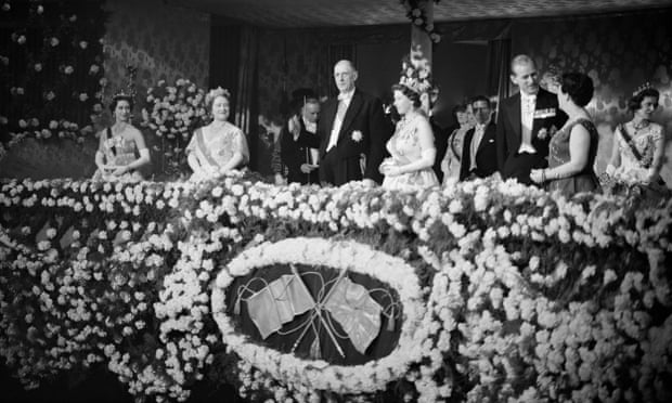 President Charles de Gaulle stands next to the Queen on a balcony decorated with carnations at the Royal Opera House, alongside the Queen Mother, the Duke of Edinburgh, Princess Margaret and others