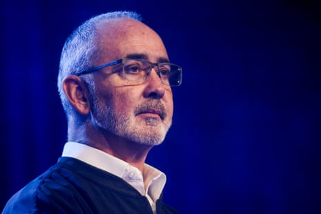 A man wearing glasses and collared shirt looks ahead