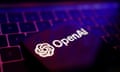 OpenAI logo on a phone, with a keyboard in the background