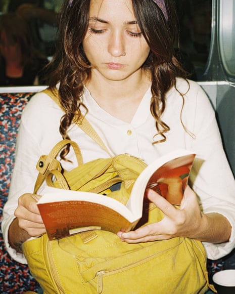 Young woman reading book in subway, shot with flash on film