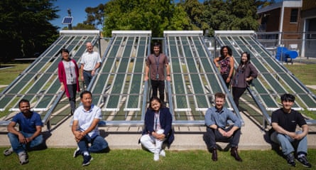 Ten people sitting and standing near solar panels