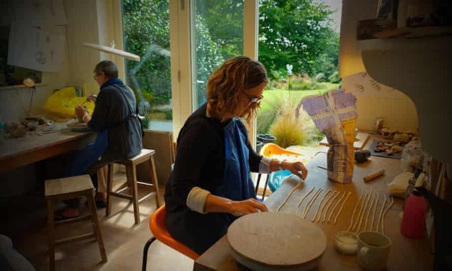 A studio shot showing two women at desks making pottery