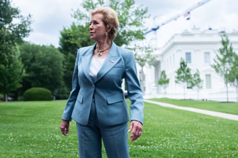 A woman in a blue suit stands on a lawn.