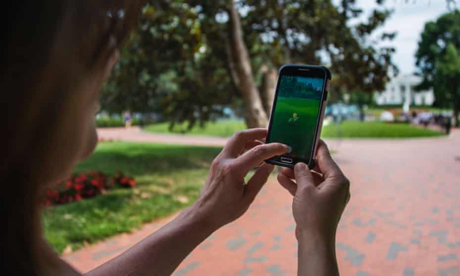 A woman holds up her mobile phone as she plays Pokémon Go.